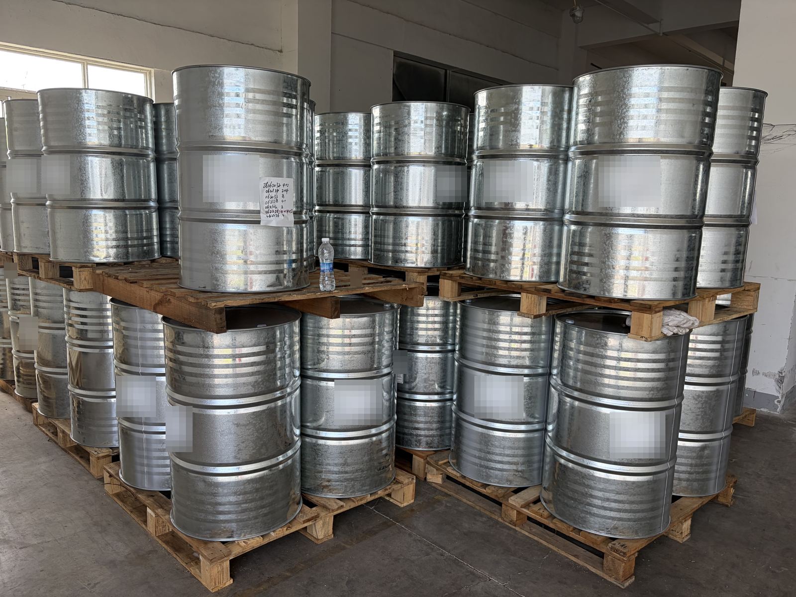 Steel drums stacked on wooden pallets in a warehouse